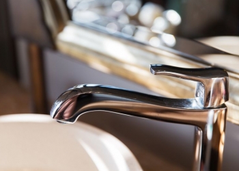 sanitary, plumbing and washing concept - close up of bath tap or faucet at bathroom