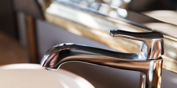 sanitary, plumbing and washing concept - close up of bath tap or faucet at bathroom