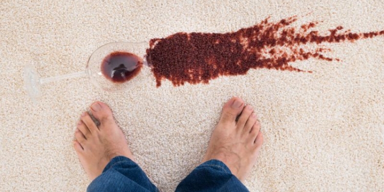 37025087 - close-up of a person's feet standing near red wine spilled on carpet