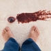 37025087 - close-up of a person's feet standing near red wine spilled on carpet