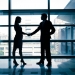 27342987 - successful business woman and man handshaking with office building