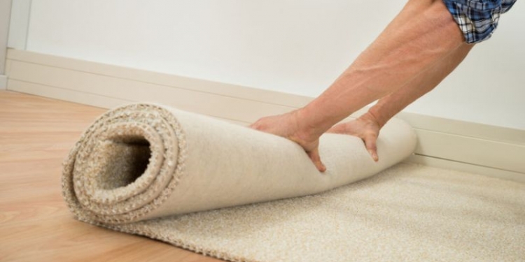 40871193 - close-up of a male worker folding carpet on floor at home