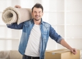 38295256 - the young happy man keeping carpet. moving, purchase of new habitation.