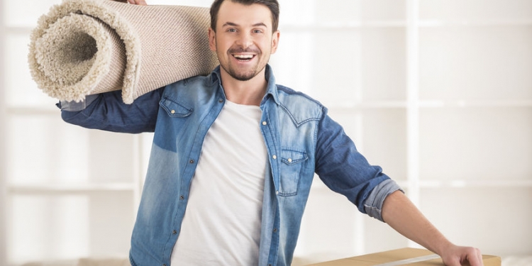 38295256 - the young happy man keeping carpet. moving, purchase of new habitation.