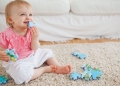 10074371 - blond baby playing with puzzle pieces while sitting on a carpet in the living room