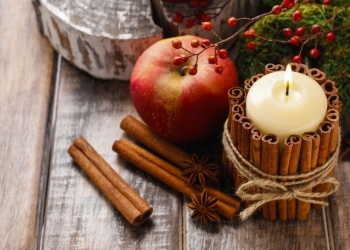 Candle decorated with cinnamon sticks and red apples, christmas decoration
