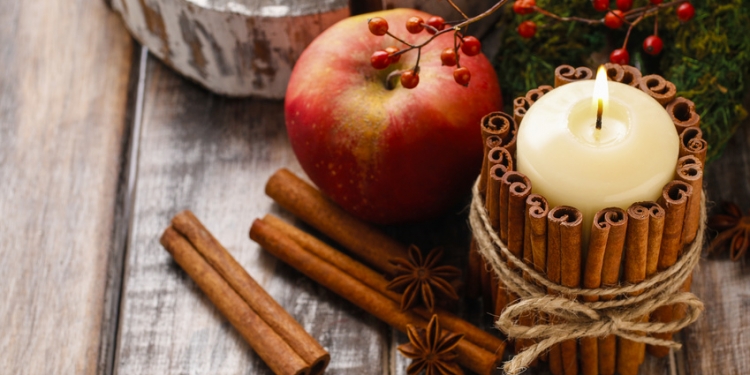 Candle decorated with cinnamon sticks and red apples, christmas decoration