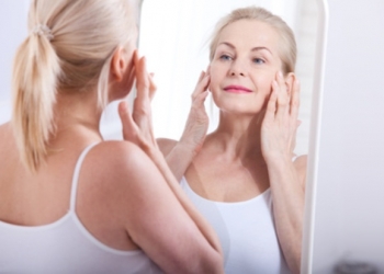 Middle aged woman looking at wrinkles in mirror. Plastic surgery and collagen injections. Makeup. Macro face. Selective focus