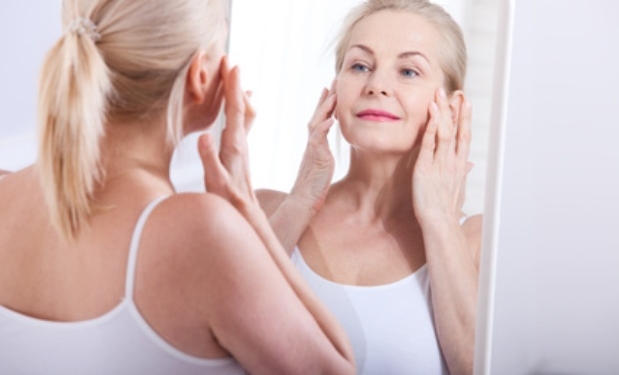 Middle aged woman looking at wrinkles in mirror. Plastic surgery and collagen injections. Makeup. Macro face. Selective focus