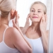 Middle aged woman looking at wrinkles in mirror. Plastic surgery and collagen injections. Makeup. Macro face. Selective focus