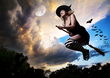 Wicked witch flying on broomstick with bats behind her and moon nearby in the evening dramatic sky background. Free space for text