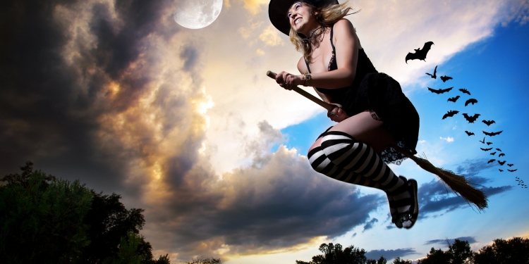 Wicked witch flying on broomstick with bats behind her and moon nearby in the evening dramatic sky background. Free space for text