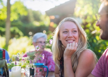 In summer a family of three generations gathers to share a meal in the garden. closeup on a beautiful young blonde woman smiling at her boyfriend