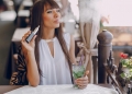 beautiful brunette smoke electronic cigarette on the summer terrace of restaurant